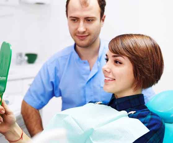Woman smiling in the mirror at the dentist’s office
