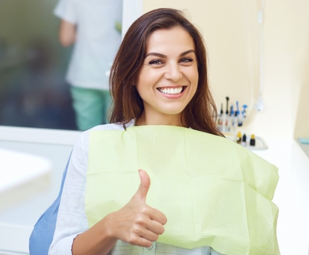 Woman giving thumbs up after oral surgery
