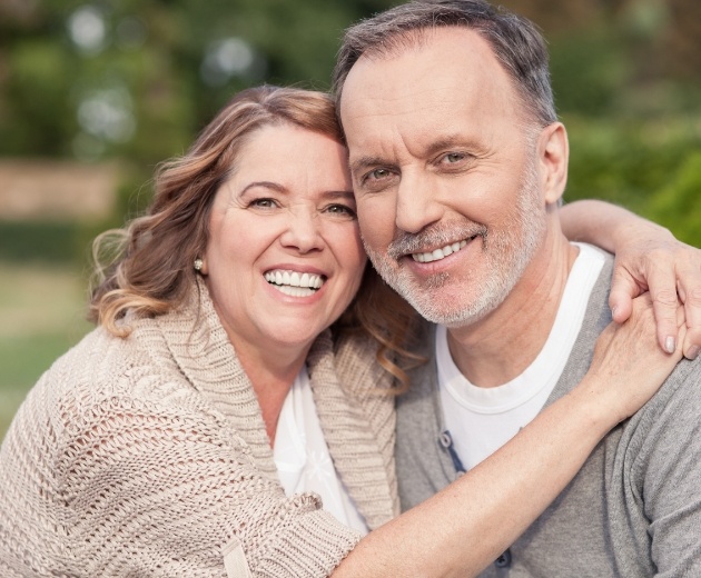 Man and woman smiling after tooth extractions