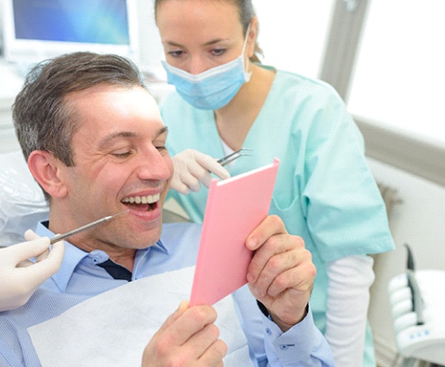 Man admiring his smile after full mouth restoration in Alexandria