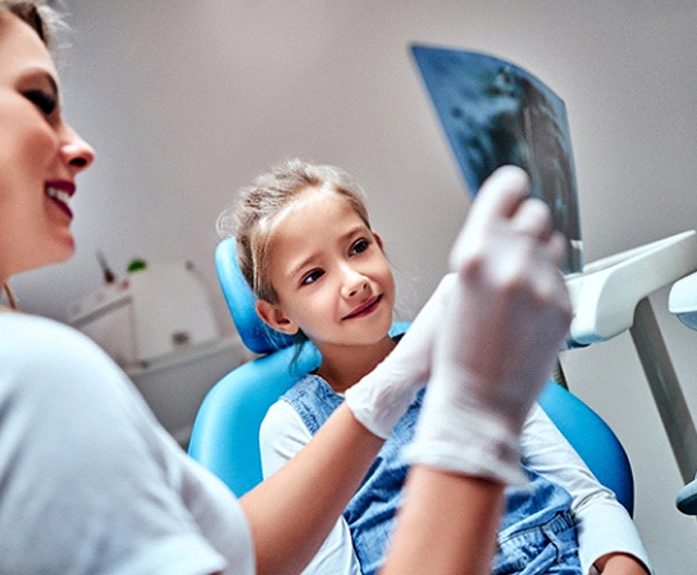 Dental team member and little girl reviewing X-Ray
