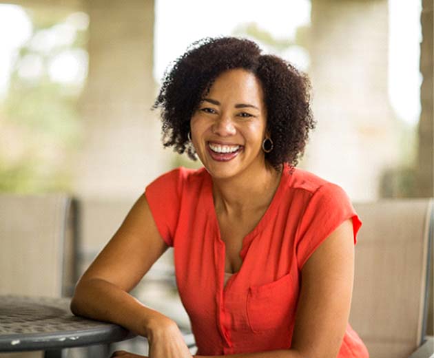 Woman in red shirt smiling while sitting outside