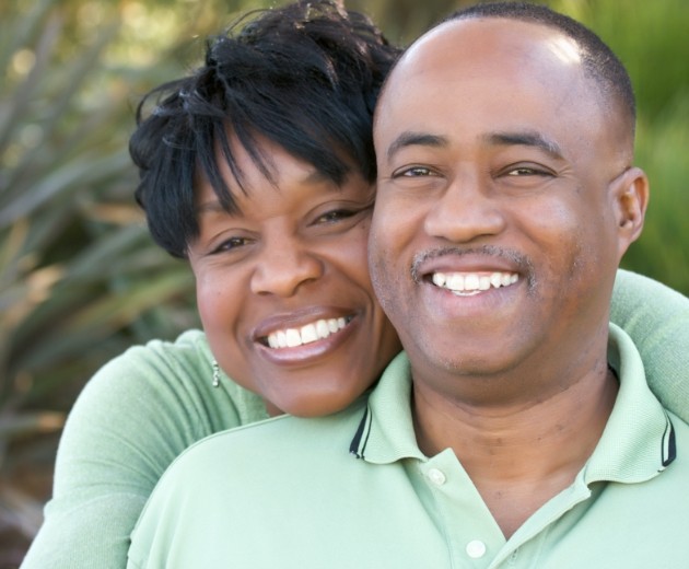 Man and woman smiling after full mouth restorations