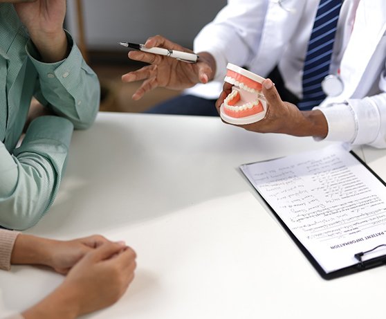 an oral surgeon showing patients a model of a mouth