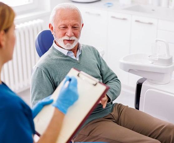 Dental team member taking notes during patient consultation