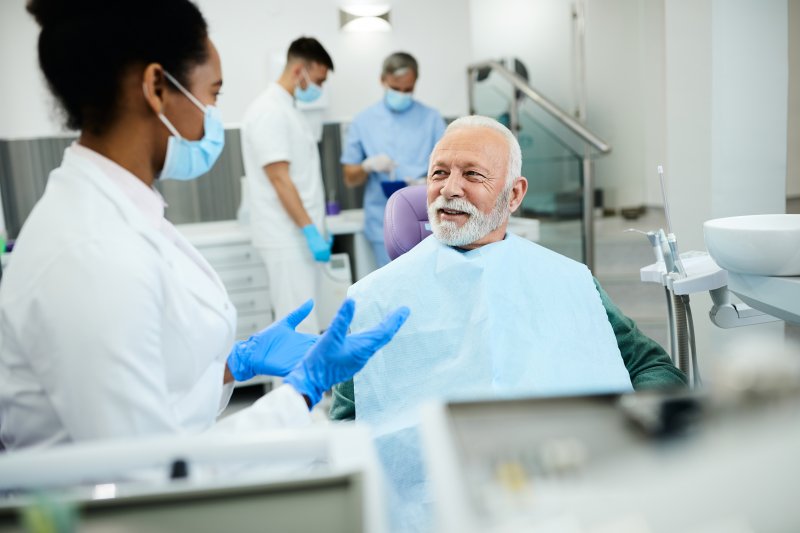 Oral surgeon explaining dental implant cost factors to older patient