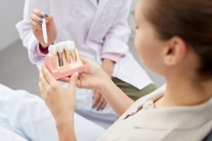 Patient holding a model of dental implants