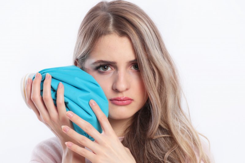 young woman holding an ice pack to her jaw 