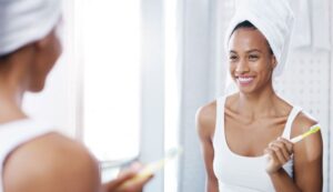 Smiling woman in front of mirror, holding toothbrush