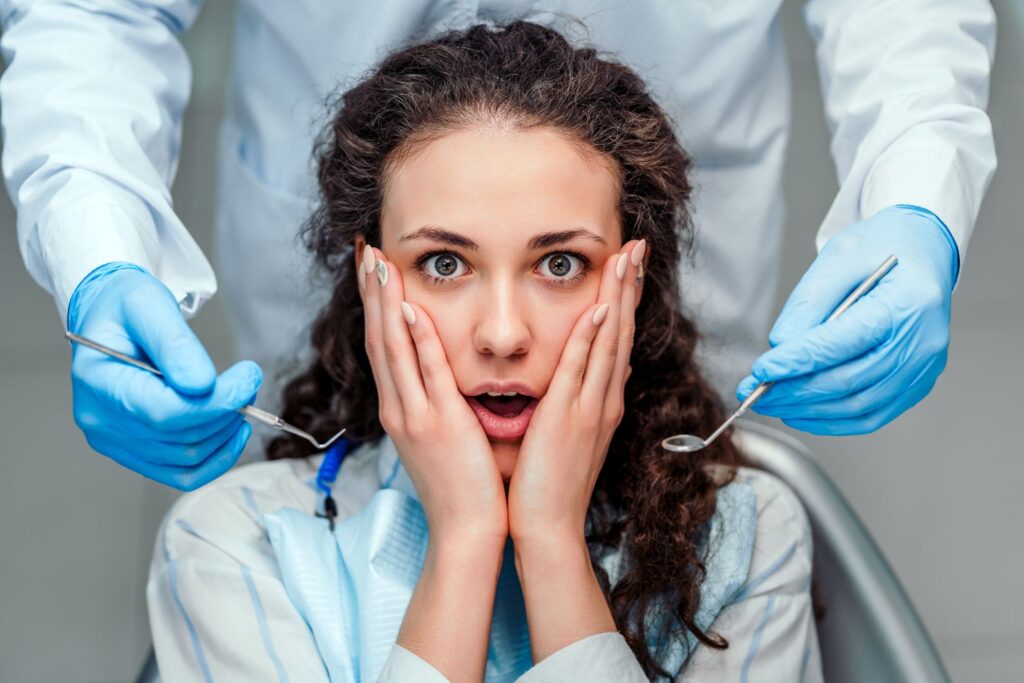 A woman covering her mouth in fear at the dentist