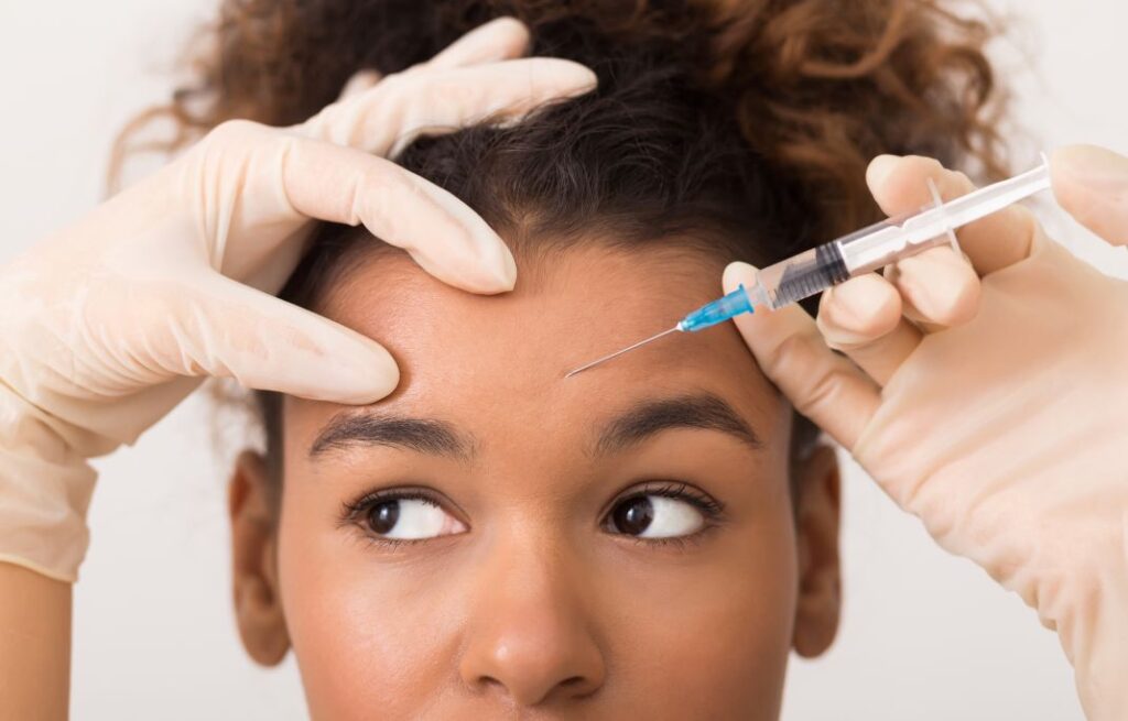A woman getting a BOTOX injection in her forehead